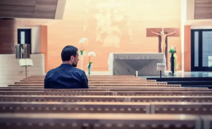 Young man praying in church. By ZoneCreative/stock.adobe.com