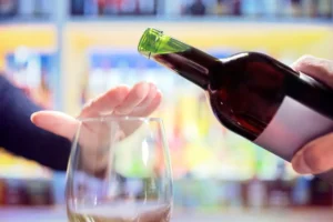 Woman's hand rejecting alcohol from wine bottle in bar to illustrate the Surgeon General's new warning of the link between alcohol and cancer. By Brian Jackson/stock.adobe.com