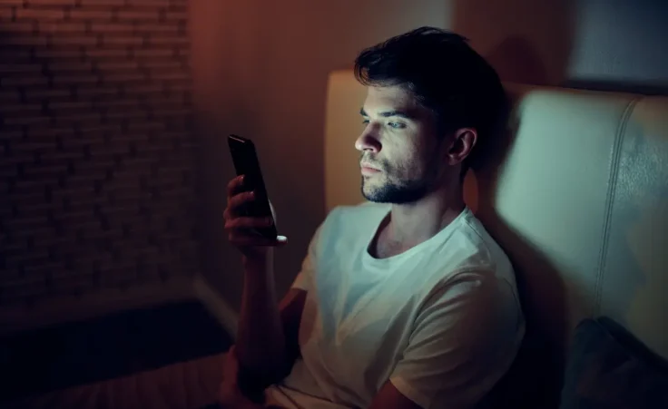 Portrait of young man sitting on sofa at home. By SHOTPRIME STUDIO/stock.adobe.com