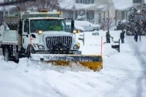 A snowplow truck clearing the roadways of snow after the winter storm covered streets in urban area. By Philip/stock.adobe.com
