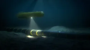 Autonomous underwater vehicle (AUV) rover-drone inspecting a submarine internet communication cable on the seabed in the ocean. By Jesper/stock.adobe.com
