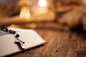 The Cross, monstrance, Holy Bible and golden chalice on wooden altar. By zolnierek/stock.adobe.com