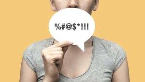 A person holding a word bubble with obscene expressions. By fidaolga/stock.adobe.com