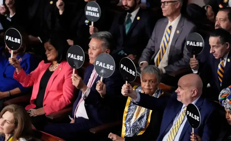 Members of Congress hold up signs as President Donald Trump addresses a joint session of Congress at the Capitol in Washington, Tuesday, March 4, 2025. (AP Photo/J. Scott Applewhite)