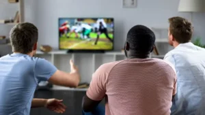 Male friends gather to watch football competition on big screen, sofa experts By motortion/stock.adobe.com