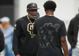 Colorado head coach Deion Sanders, left, talks with his son, quarterback Shedeur Sanders before passing drills at Colorado's NFL football pro day Friday, April 4, 2025, in Boulder, Colo. (AP Photo/David Zalubowski)