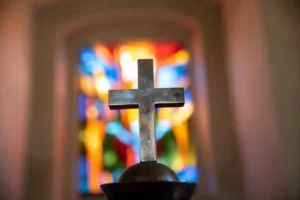 Cross in a church on a pulpit dimly lit by stained glass windows. By flordigitalartist/stock.adobe.com Josh Sullivan