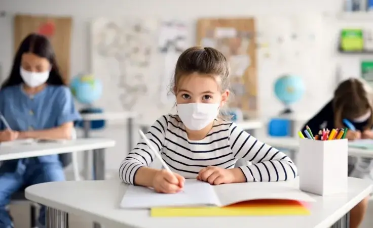 Child with face mask back at school after covid-19 quarantine and lockdown. By Halfpoint/stock.adobe.com