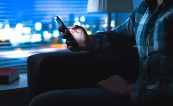 Man using phone late at night to illustrate the dangers of pornography access on mobile devices. By terovesalainen/stock.adobe.com