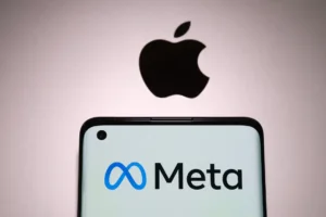 Meta company logo seen on smartphone which is plased on top of Macbook with blurred apple logo. By Ascannio/stock.adobe.com
