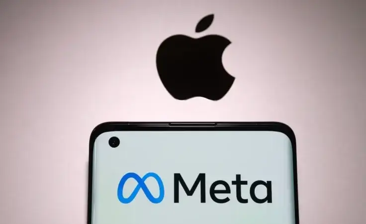 Meta company logo seen on smartphone which is plased on top of Macbook with blurred apple logo. By Ascannio/stock.adobe.com