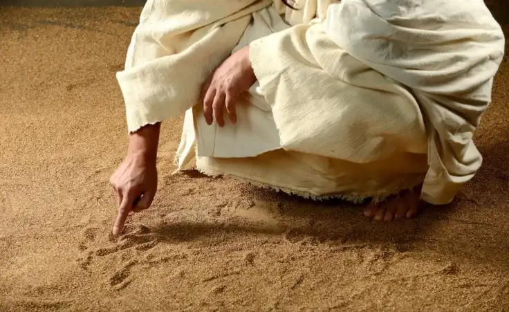 Jesus writing on the sand before his act of great compassion in John 8. By Carlos Santa Maria/stock.adobe.com