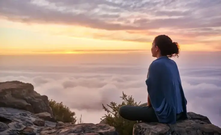 A woman on a mountain top looking at morning clouds. By marvent/stock.adobe.com. Decline of woke culture