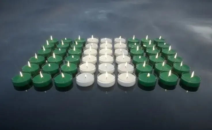 Candles with the colors of the Nigerian flag. In memory of the victims. By Negro Elkha/stock.adobe.com