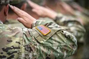 Detail shot with american flag on soldier uniform, giving the honor salute during military ceremony By roibu/stock.adobe.com