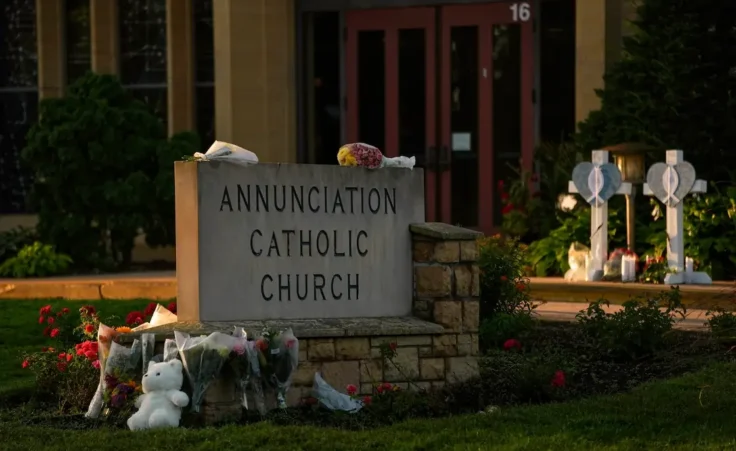 Crosses, flowers and other mementos were places by the sign at Annunciation Catholic Church at a memorial after Wednesday's shooting at the school, Thursday, Aug. 28, 2025, in Minneapolis. (AP Photo/Abbie Parr)