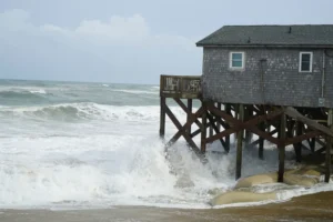 Waves from Hurricane Erin crash against the sandbagged pilings of a building in Buxton, N.C., on Wednesday, Aug. 20, 2025. (AP Photo/Allen G. Breed)