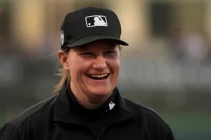 Umpire Jen Pawol smiles as she takes part in the lineup card exchange before the start of a spring training baseball game between the Washington Nationals and the Houston Astros Saturday, Feb. 24, 2024, in West Palm Beach, Fla. Pawol took a big step toward breaking the gender barrier for Major League Baseball umpires when she became the first woman in 17 years to work a big league spring training game Saturday night. (AP Photo/Jeff Roberson)