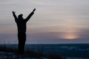 Silhouette of a man during a sunset praising God with his hands up to illustrate embracing wonder and praising God for miracles. By amdre100/stock.adobe.com