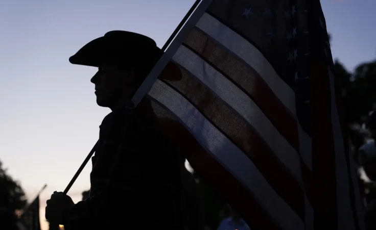 Koda holds an American flag as attendees pay their respects during a vigil for Charlie Kirk on Friday, Sept. 12, 2025, in Provo, Utah. (AP Photo/Lindsey Wasson) Turning Point