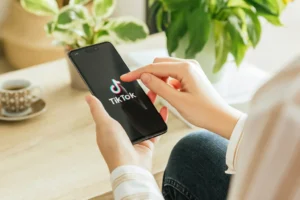 Woman using the social media app TikTok on a smartphone at home. By Azulblue/stock.adobe.com. TikTok ban