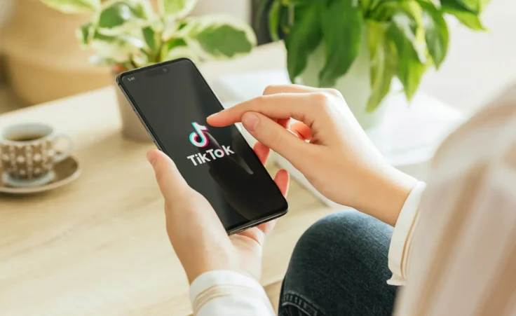Woman using the social media app TikTok on a smartphone at home. By Azulblue/stock.adobe.com. TikTok ban