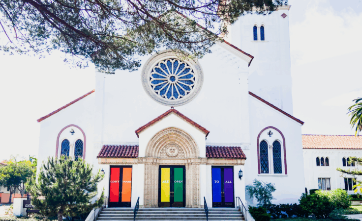 "God's Doors Are Open To All," a sign displayed on the doors of a church in support of pride month. By glimmersDarkly/stock.adobe.com. LGBTQ storybook bible social justice