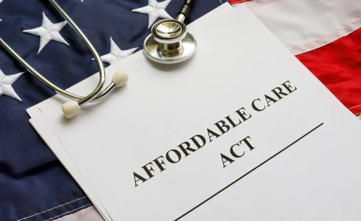 Concept image of the Affordable Care Act (ACA) bill, the American flag, and a stethoscope. By VitaliiVodolazskyi/stock.adobe.com. government shutdown subsidies obamacare