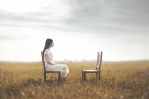 Woman sitting in front of an empty chair to illustrate the 2 Chairs concept. By Cristina Conti/stock.adobe.com