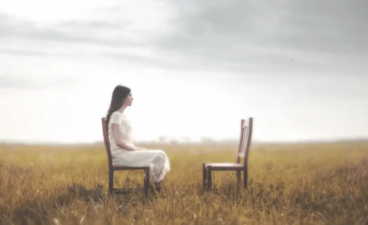 Woman sitting in front of an empty chair to illustrate the 2 Chairs concept. By Cristina Conti/stock.adobe.com
