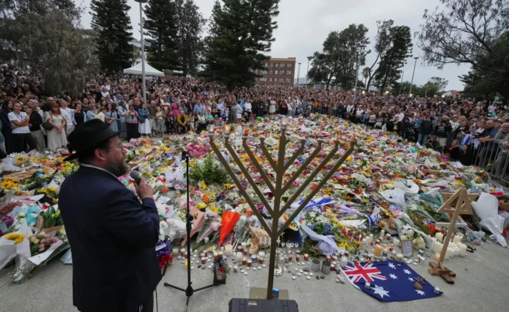 Rabbi Motti Feldman speaks at a menorah lighting ceremony at a floral memorial for victims of Sunday's shooting, at the Bondi Pavilion at Bondi Beach on Tuesday, Dec. 16, 2025, in Sydney, Australia. (AP Photo/Mark Baker)