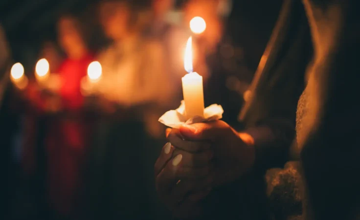 Girl holding candle during Christmas Eve church service. By evgavrilov/stock.adobe.com. church mental wellness Christmas