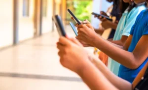 Close up shot, group of children hands busy using smartphone at school corridor - concept of social media, playing games, technology and education By WESTOCK/stock.adobe.com