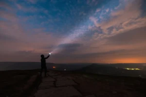 Silhouette of a woman with flashlight under the night sky with dawn on the horizon. By william87/stock.adobe.com. how to find hope in the new year