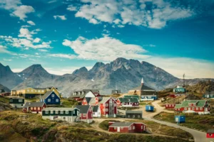 Small town on the east coast of Greenland, featuring colorful houses against a mountainous backdrop. By Elizabeth/stock.adobe.com.