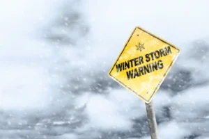 Sign that reads "Winter Storm Warning" with snowfall and a snowy background. By ronniechua/stock.adobe.com.