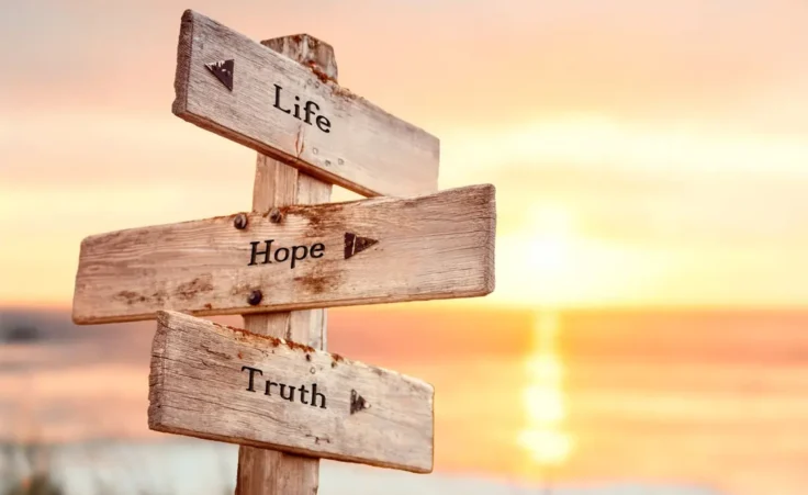 life hope truth text quote on wooden crossroad signpost outdoors on beach with pink pastel sunset colors. Romantic theme. By Jon Anders Wiken/stock.adobe.com