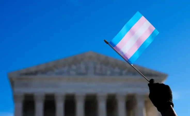 Protesters wave transgender pride flags outside the Supreme Court as it hears arguments over state laws barring transgender girls and women from playing on school athletic teams, Tuesday, Jan. 13, 2026, in Washington. (AP Photo/Julia Demaree Nikhinson)