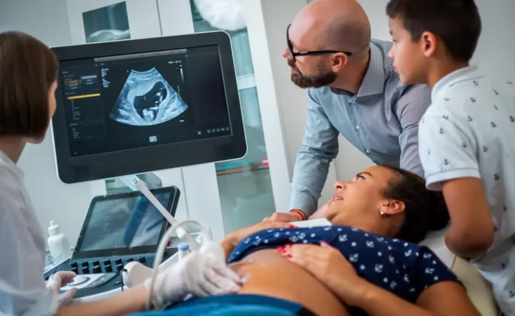 Pregnant woman and her family on utltrasonographic examination at hospital By Nejron Photo/stock.adobe.com