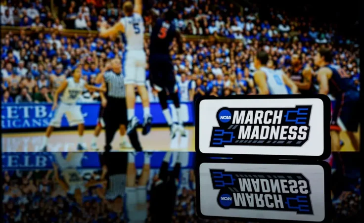 March madness logo on screen and NCAA basketball game play on TV in the background By Rokas/stock.adobe.com