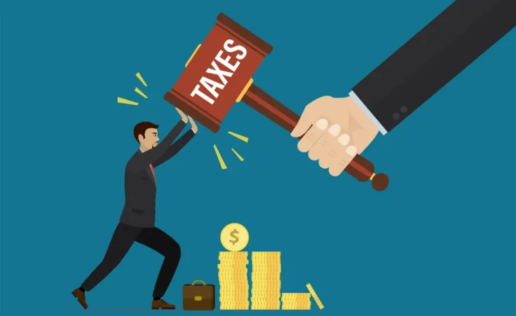 Businessman holds off additional taxes from his pile of income. By naum/stock.adobe.com. Your “Tax Freedom Day” is approaching