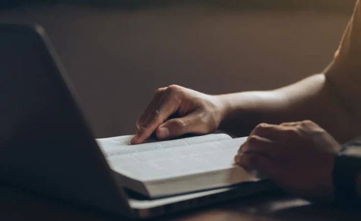 Young men concentrate on reading books with a laptop computer on the desk at home.Studying the Word Of God. bible study Concept By Pcess609