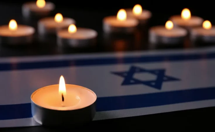 Burning candle and flag of Israel on black table. Holocaust memory day By New Africa/stock.adobe.com