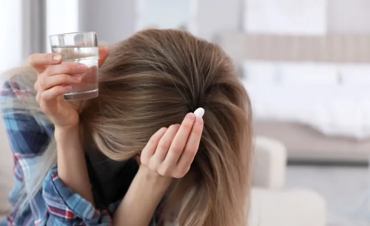 Upset young woman with abortion pill and glass of water at home By New Africa/stock.adobe.com