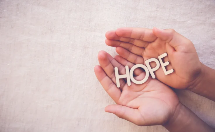 Wooden word "HOPE" on praying hands in a gratitude, faith concept. By SewcreamStudio/stock.adobe.com.