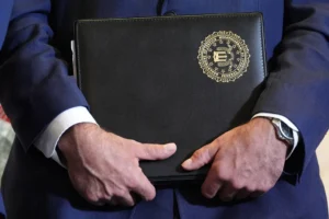 FBI Deputy Director Christopher Raia holds a folder marked with the FBI logo during an event where federal prosecutors announced charges against former Cuban President Raul Castro in the 1996 downing of civilian planes operated by Miami-based exiles, Wednesday, May 20, 2026, in Miami. (AP Photo/Rebecca Blackwell)
