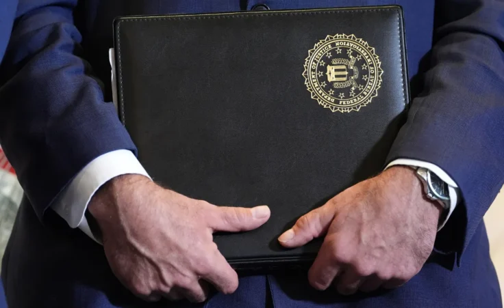 FBI Deputy Director Christopher Raia holds a folder marked with the FBI logo during an event where federal prosecutors announced charges against former Cuban President Raul Castro in the 1996 downing of civilian planes operated by Miami-based exiles, Wednesday, May 20, 2026, in Miami. (AP Photo/Rebecca Blackwell)