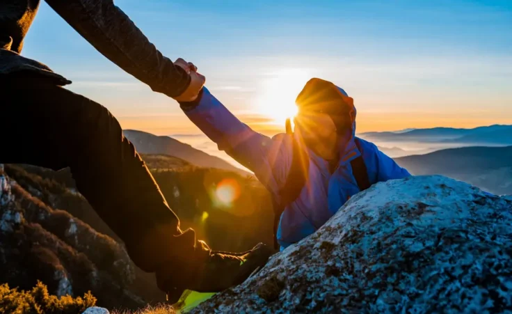 Hiking team people helping each other friend giving a helping hand while climbing up on the mountain rock adventure travel concept of friendship support trust teamwork success. By Malik Nalik/stock.adobe.com