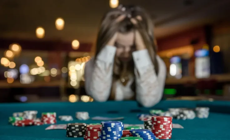 Upset woman in casino sitting behind poker table by RomanR/stock.adobe.com