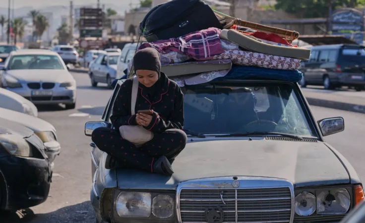 A displaced woman checks her mobile phone as she waits to return to her village following the announcement of an initial ceasefire agreement between the United States and Iran, in the southern port city of Sidon, Lebanon, Monday, June 15, 2026. (AP Photo/Mohammed Zaatari)